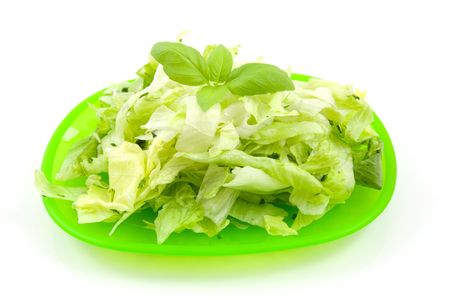 plate with green fresh lettuce salad over white backgroundの写真素材