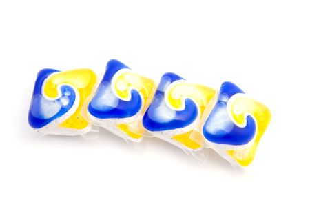 blue and yellow colored dishwasher tablets isolated on white backgroundの写真素材