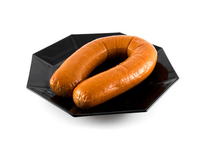 Black plate with fresh sausage over white backgroundの写真素材