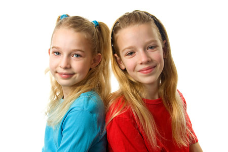 Two young blonde girls looking in camera over white backgroundの写真素材