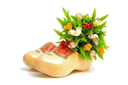 pair of traditional Dutch yellow wooden shoes with little tulips over white background