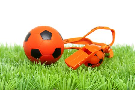 Orange soccer ball ans flute on grass over white backgroundの写真素材