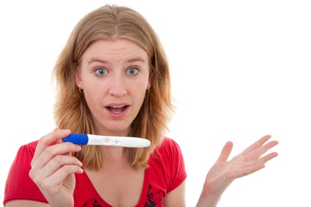 Woman is happy because she is pregnant and is showing her test with big eyes over white backgroundの写真素材