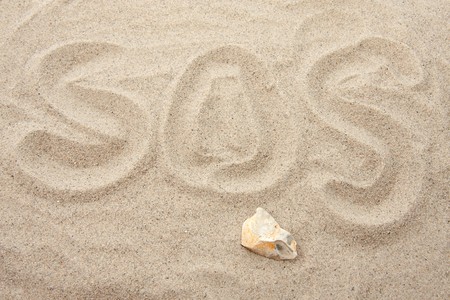 SOS letters written in sand in closeupの写真素材