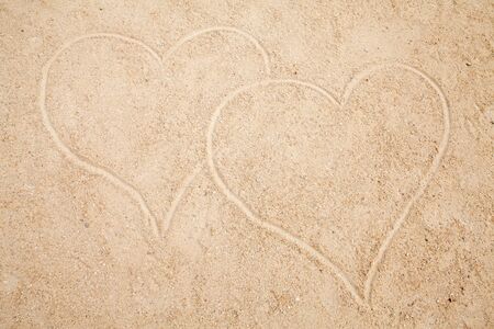 two hearts drawn in sand in closeupの写真素材
