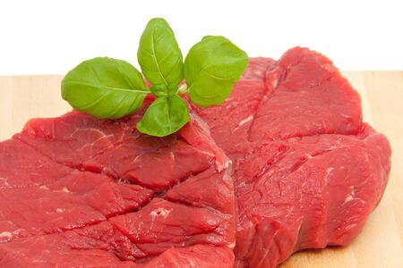 raw steak meat on cutting board in closeup over white backgroundの写真素材