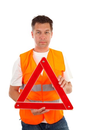 Man in safety vest holding foldaway reflective road hazard warning triangle over white backgroundの写真素材