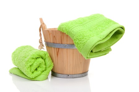 wooden bucket for spa or sauna with green towels over white backgroundの写真素材