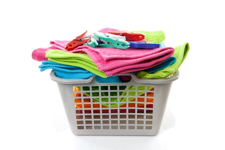 Laundry basket filled with colorful towels and pegs over white backgroundの写真素材
