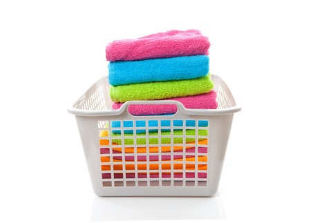 Laundry basket filled with colorful folded towels over white backgroundの写真素材