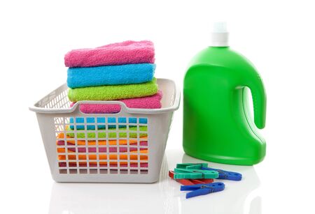 Laundry basket filled with colorful folded towels, pegs and bottle over white backgroundの写真素材