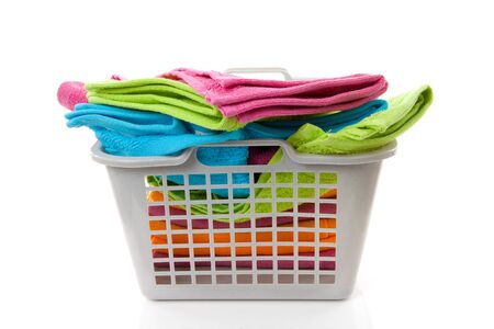 Laundry basket filled with colorful towels over white backgroundの写真素材