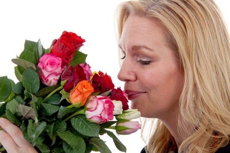 woman is smelling bouquet of colorful roses over white backgroundの写真素材