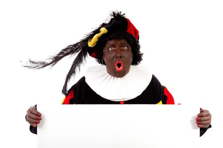 Zwarte piet ( black pete) typical Dutch character part of a traditional event celebrating the birthday of Sinterklaas in december over white background is holding empty text boardの写真素材