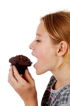 Girl is eating big chocolate cupcake over white backgroundの写真素材