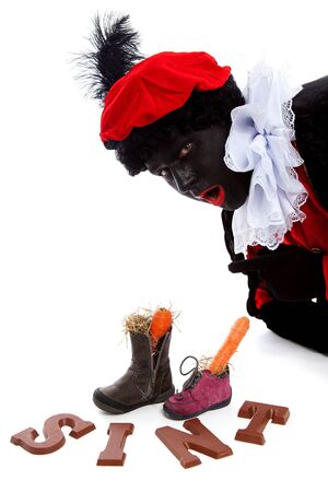 Sinterklaas, typical Dutch event with zwarte piet ( black pete) chocolate letters and carrot in shoes over white backgroundの写真素材