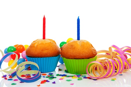 Birthday cupcakes with lots of candles, party streamers and colorful confetti over white backgroundの写真素材