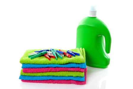 colorful folded towels, pegs and bottle over white backgroundの写真素材