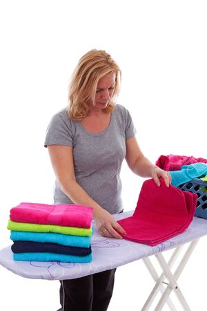 Housewife is folding colorful towels over white backgroundの写真素材