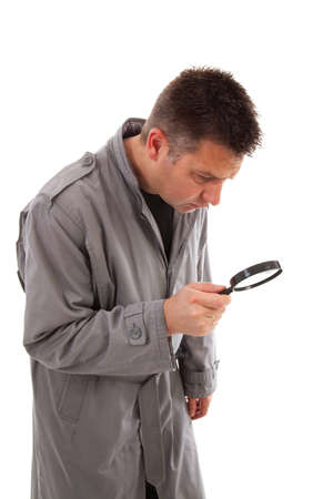 Man with raincoat is looking with magnifying glass over white backgroundの写真素材