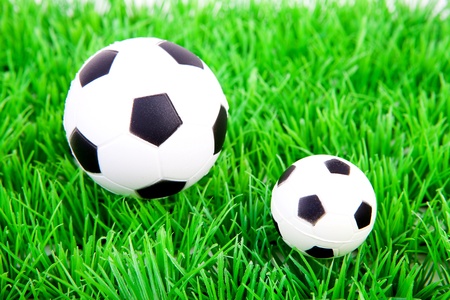 One big and one little soccer ball on plastic grass の写真素材