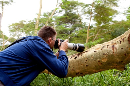 Paparazzi man making photo behind treeの写真素材