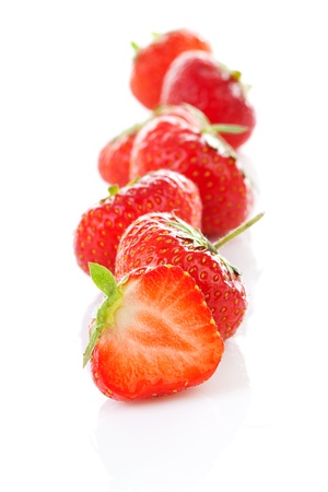 Row of fresh strawberries in closeup over white backgroundの写真素材
