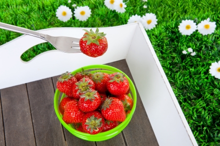 Fresh strawberries in bowl on tray and grass over white backgroundの写真素材