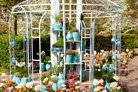 Garden house arbor with lots of blue pots and colorful flowers on sunny dayの写真素材
