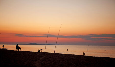 Silhouette of fishermen at sea by sunsetの写真素材