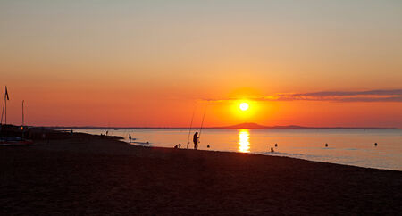 Silhouette of fishermen at sea by sunsetの写真素材