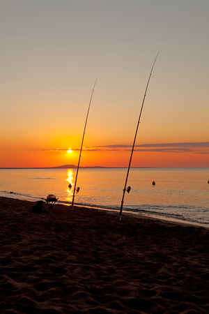 Couple of fishing rod at sea by sunsetの写真素材