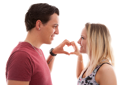 Young couple in lovemaking heart with hands over white backgroundの写真素材