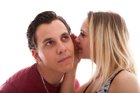 girl is whispering in ear of boyfriend isolated on white backgroundの写真素材