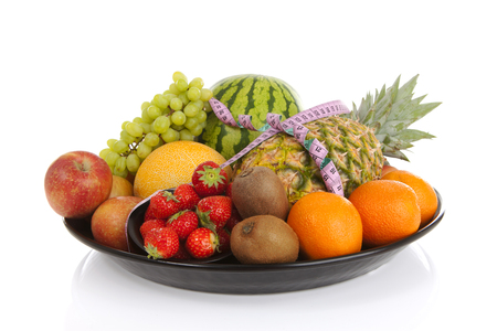 Big plate with lots of healthy fruits andmeasure tape over white backgroundの写真素材