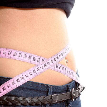 diet, young woman is measuring her waist in closeup over white backgroundの写真素材