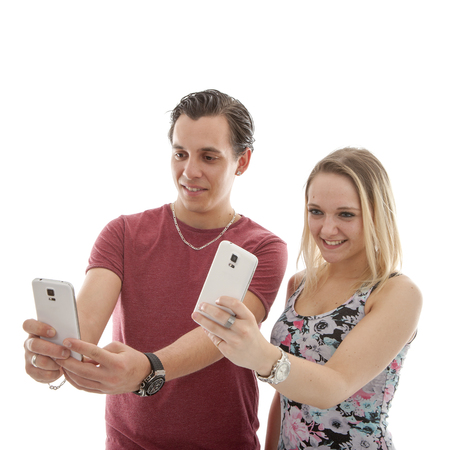 Young couple making selfie with two phones over white backgroundの写真素材