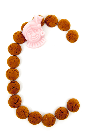 Ginger nuts, pepernoten, in the shape of letter C isolated on white background. Typical Dutch candy for Sinterklaas event in decemberの写真素材