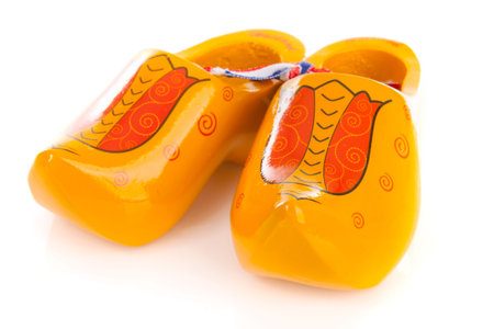 Pair of yellow Dutch wooden shoes over white background