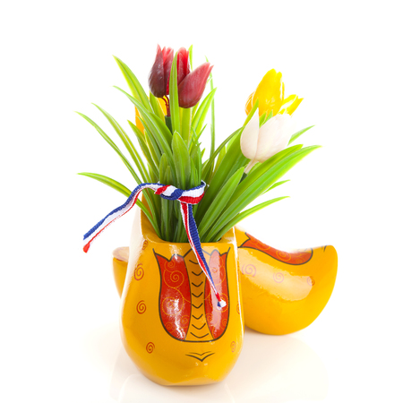 Pair of typical Dutch wooden shoes with tulips over white backgroundの写真素材