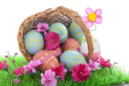 Basket full with colorful easter eggs on grass over white backgroundの写真素材