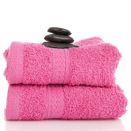 Two pink towels with black pebbles on top over white backgrouondの写真素材