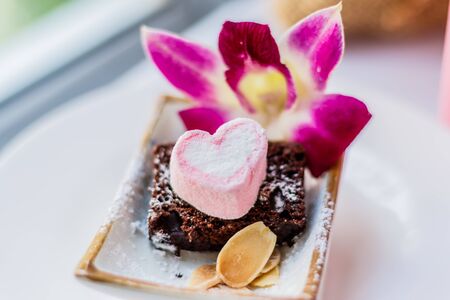 Pink and white heart-shaped candy on chocolateの写真素材