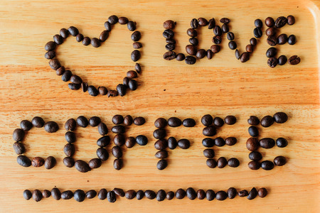 Coffee beans are literally "Love coffee" on a wooden floor.の写真素材