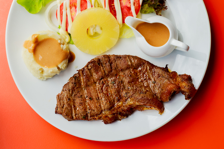 Grilled pork steak French fries and sauce on White plateの写真素材