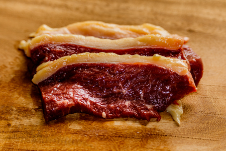 Raw fresh pork meat on cutting board on wooden tableの写真素材