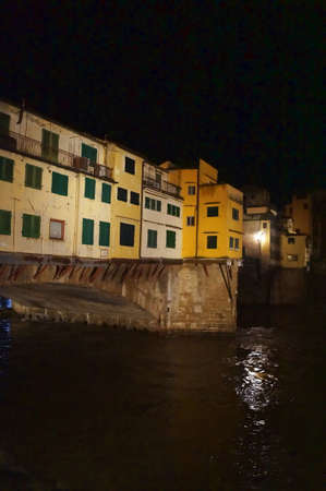 Ponte Vecchio bridge with the Arno river in flood at night in Florence, Italyの写真素材