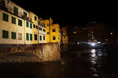 Ponte Vecchio bridge with the Arno river in flood at night in Florence, Italyの写真素材