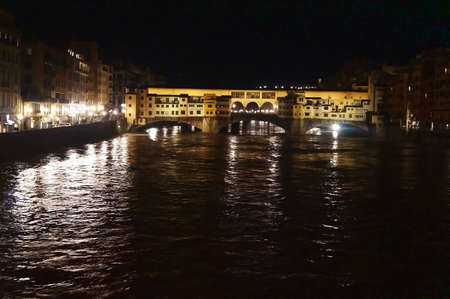 Ponte Vecchio bridge with the Arno river in flood at night in Florence, Italyの写真素材