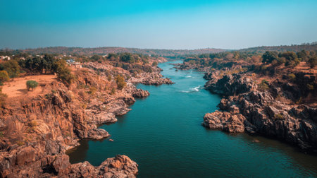 Experience the beauty of a tranquil river winding through rocky formations, lush greenery, and clear skies, perfect for nature lovers.の素材